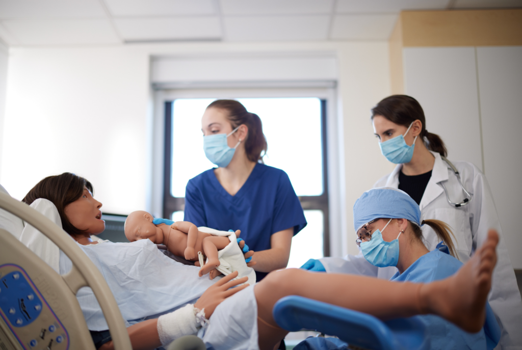 Clinicians practicing emergency obstetric procedures on Lucina maternal simulator in a simulation environment.